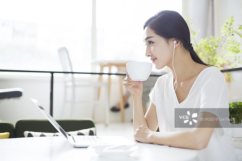 快乐的年轻女子在咖啡店听音乐图片素材