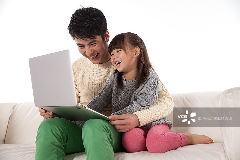 父亲和女儿坐在沙发上使用掌上电脑图片素材