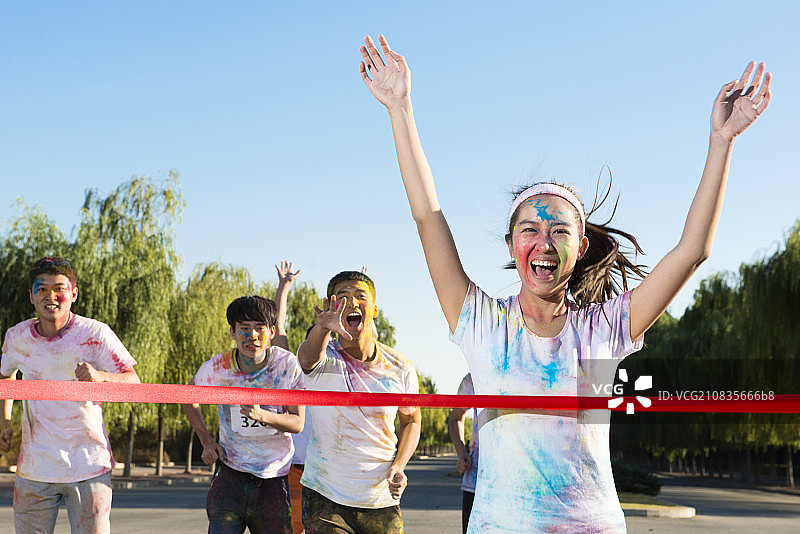 Young woman crossing finishing line at The Color Run图片素材