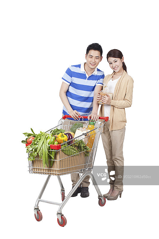 一对青年男女手拿面包和一辆装满蔬菜的购物车图片素材