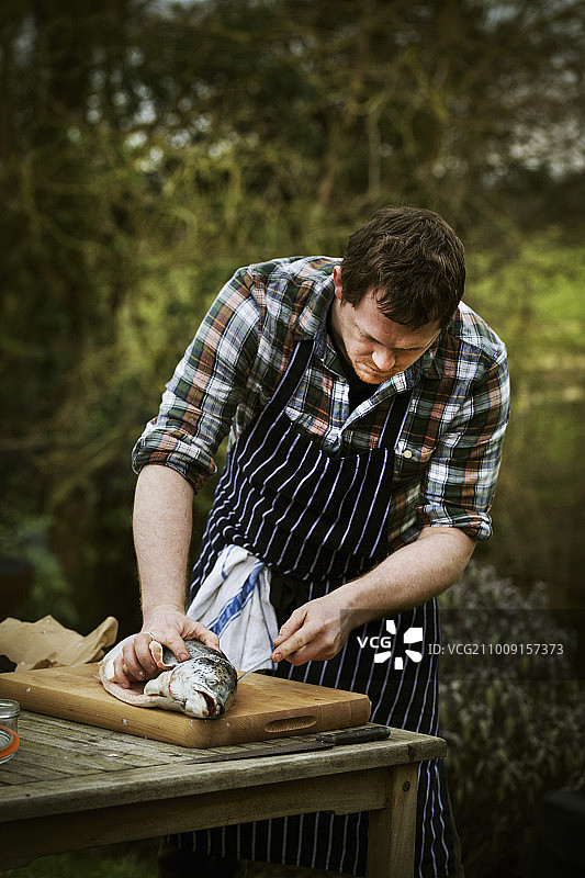 厨师在花园的桌子旁切新鲜的三文鱼图片素材