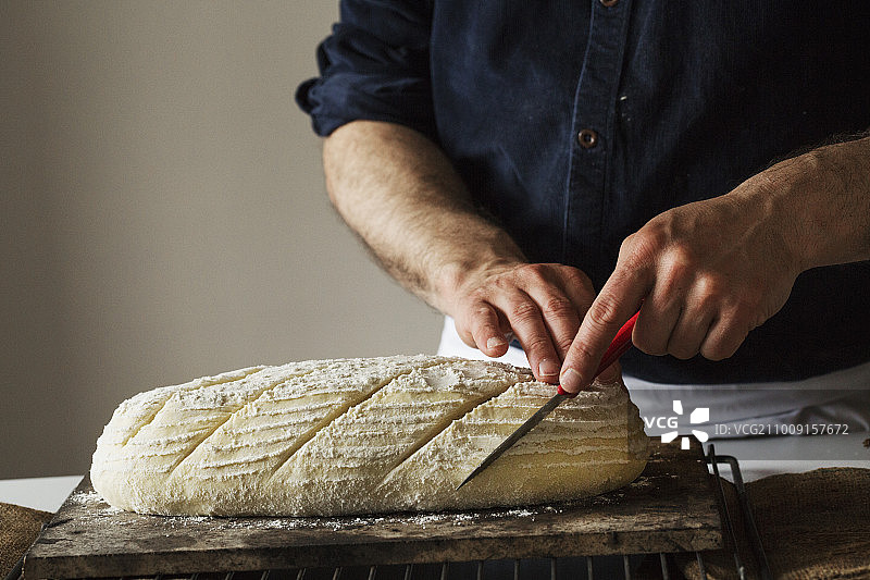 面包师用面包刀切新鲜出炉的面包特写图片素材