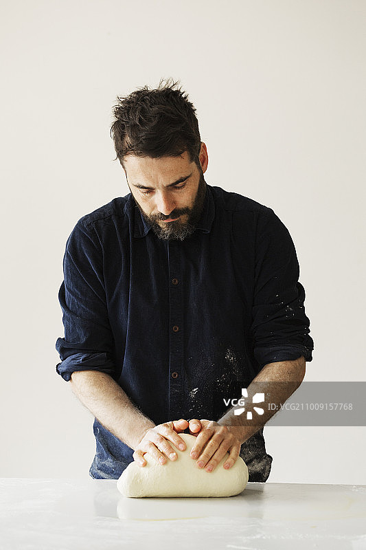 面包师揉捏一块面团并将其塑成球状图片素材