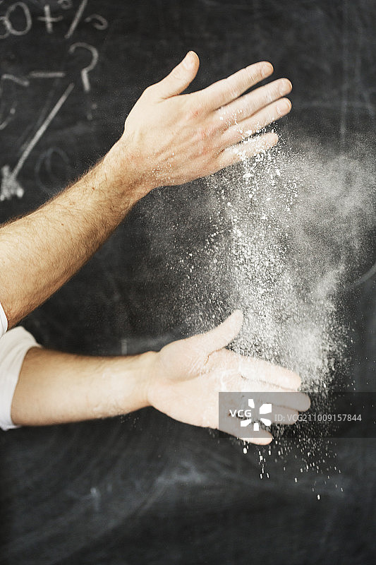 面包师站在黑板前，双手沾满面粉的特写图片素材