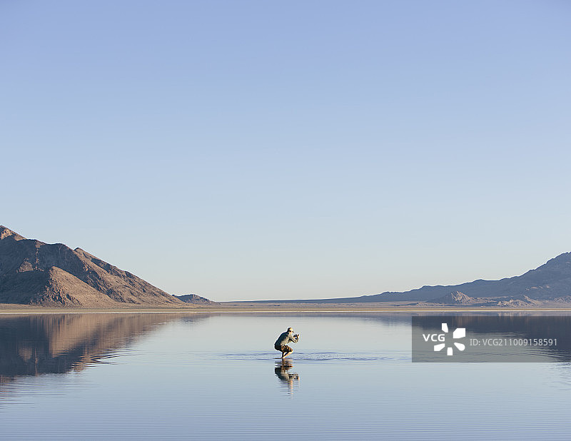 男人走在犹他州广阔且被洪水淹没的博纳维尔盐滩上图片素材