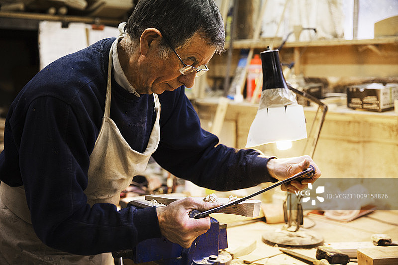 男子在木工车间的长凳上用虎钳固定木头图片素材