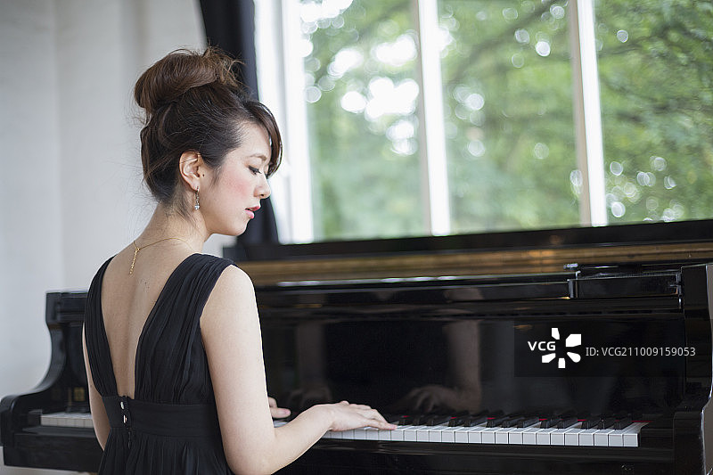年轻女人在排练厅弹奏大钢琴图片素材