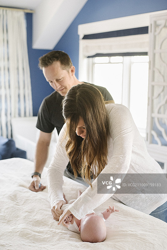 父母，母亲和父亲在更换尿布台旁，给婴儿换尿布图片素材