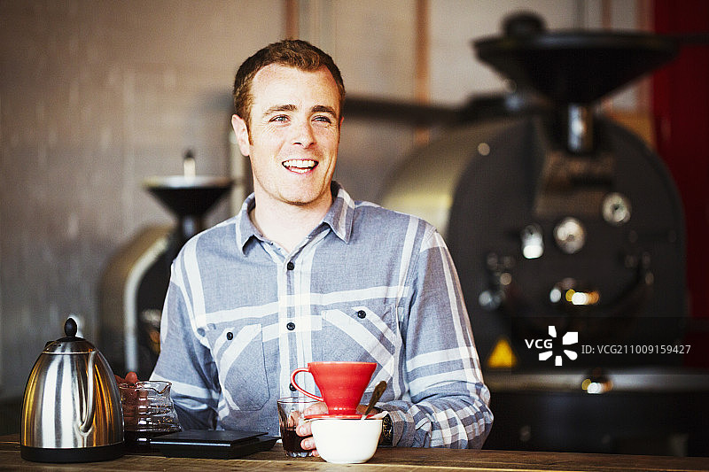 特色咖啡店：男人用滤纸冲泡咖啡并品尝图片素材