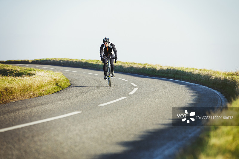阳光明媚的冬日，骑行者在乡间小路上骑行图片素材