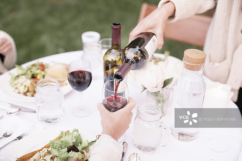 花园餐桌旁女人倒红酒特写图片素材