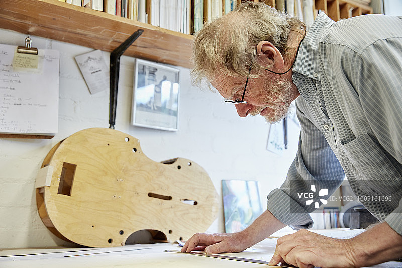 小提琴制造师在绘图板上绘制新乐器的设计图图片素材