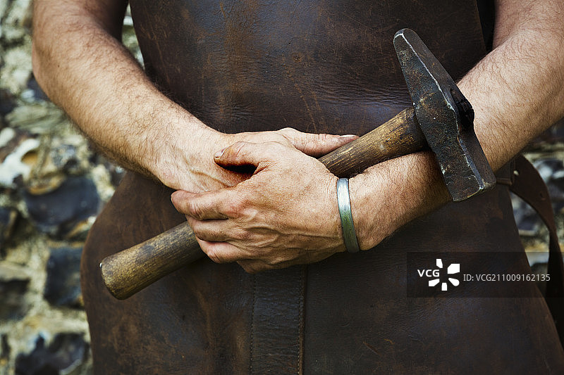 戴着皮围裙的男人拿着锤子图片素材
