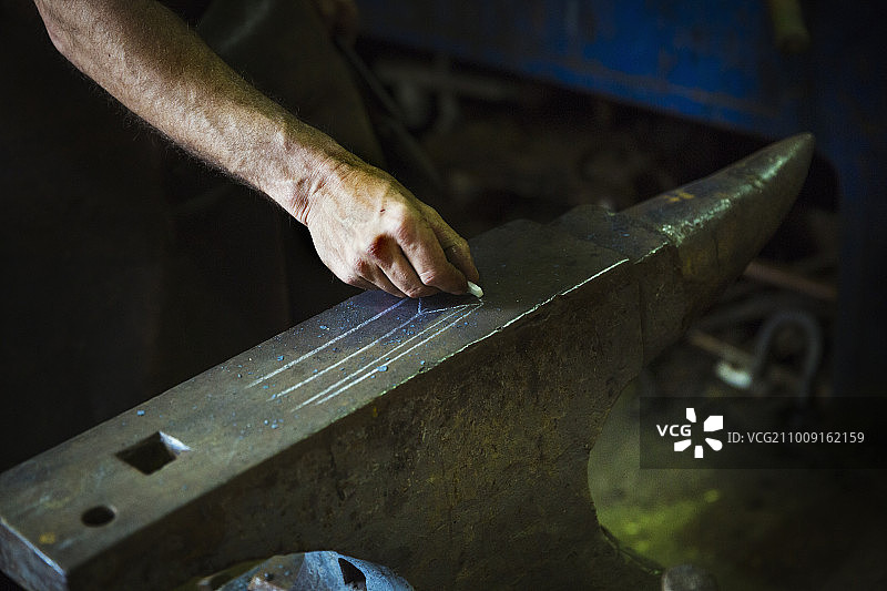 铁匠用粉笔在铁砧上绘制图案图片素材