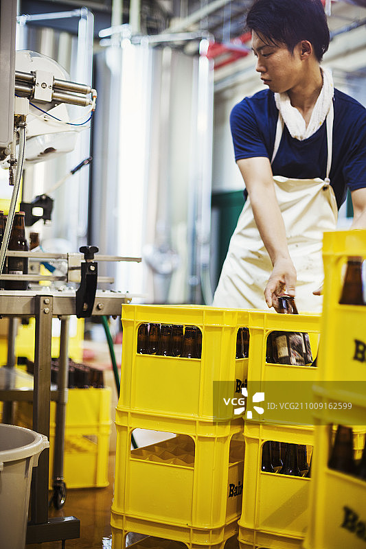工人在啤酒厂将啤酒瓶放入黄色箱子图片素材