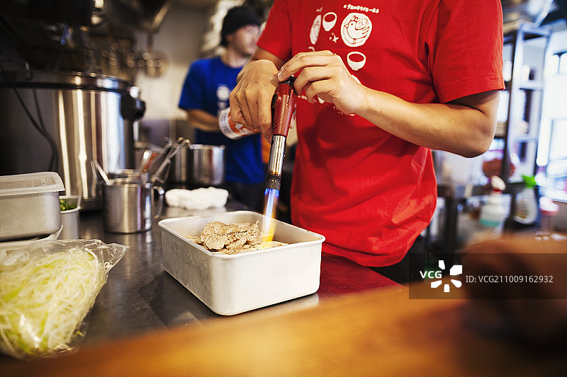 城市里的拉面馆：厨师用喷枪为肉类料理图片素材