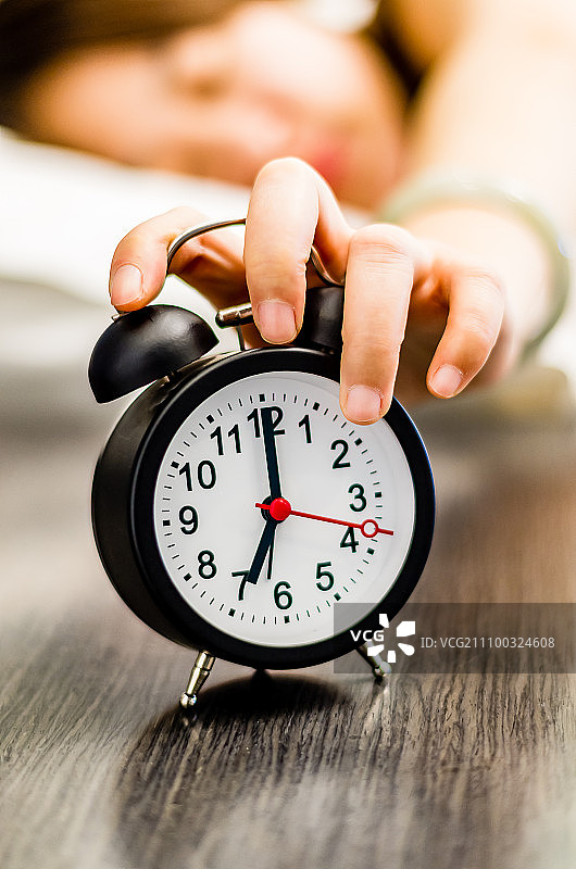 早上室内用手按着钟表的女人图片素材