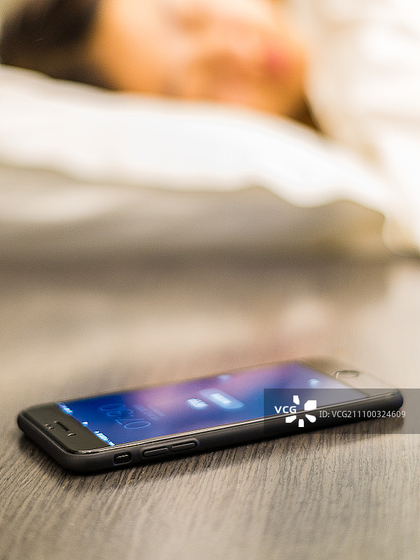 早上女士床边桌子上放的闹钟手机图片素材