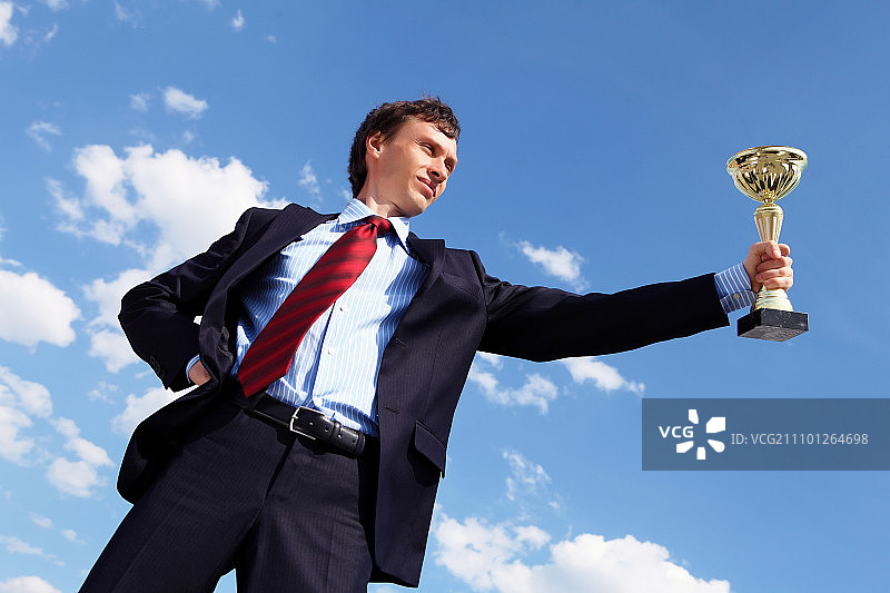 身穿西装手拿金杯的年轻商人图片素材