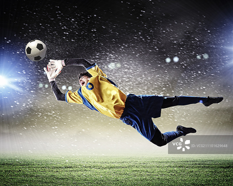 聚光灯下的体育场里，守门员接住了球图片素材
