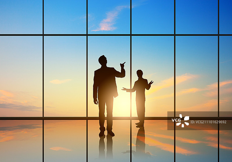 办公室会议：商务人士在全景办公室窗口前的剪影图片素材