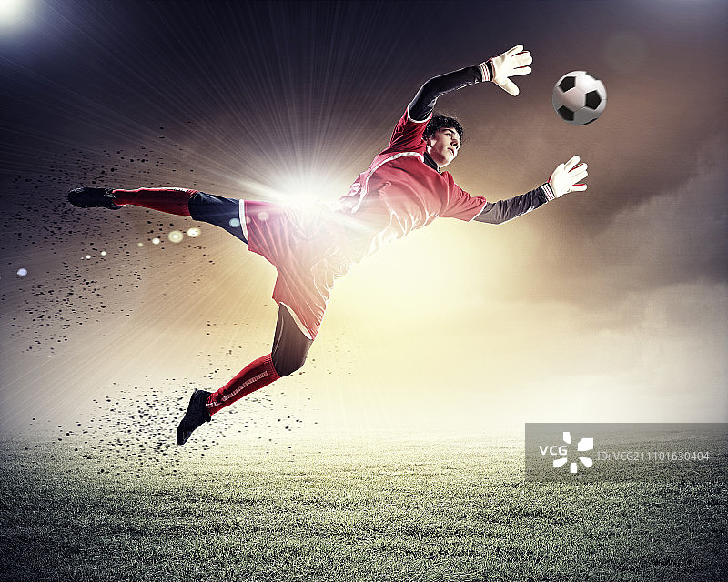 聚光灯下的体育场里，守门员接住了球图片素材