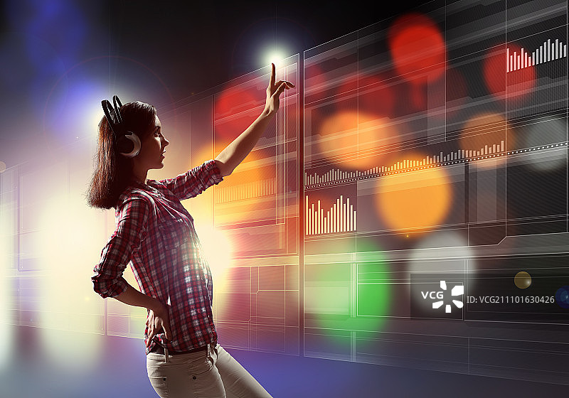 女人触摸虚拟屏幕。戴着耳机的年轻女人触摸虚拟屏幕图片素材