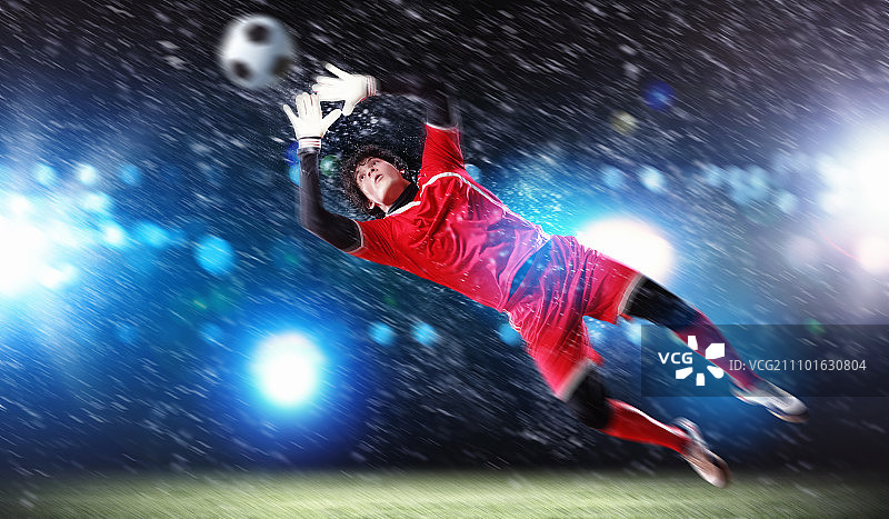 聚光灯下的体育场里，守门员接住了球图片素材