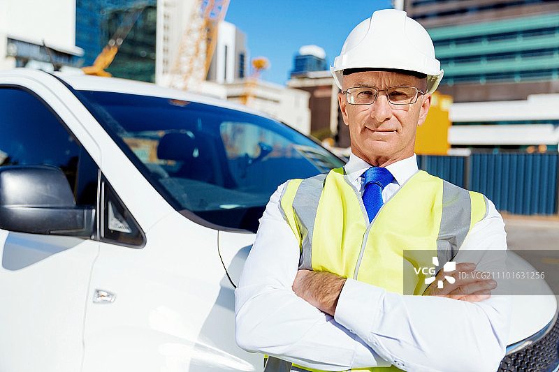 建筑工地的工程师，身穿安全背心站在白色货车旁图片素材