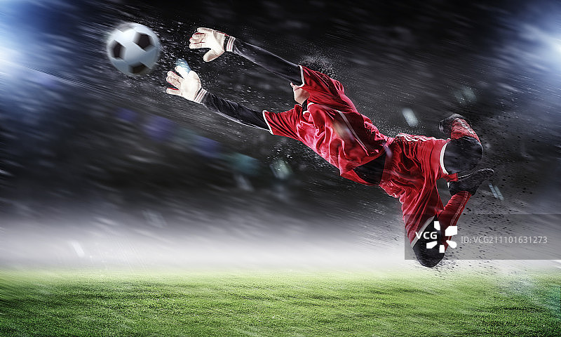聚光灯下的体育场里，守门员接住了球图片素材