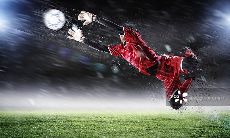 聚光灯下的体育场里，守门员接住了球图片素材