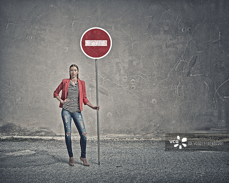 拿着停止标志的女人。穿着红色夹克站立并举着停止标志的年轻女士图片素材