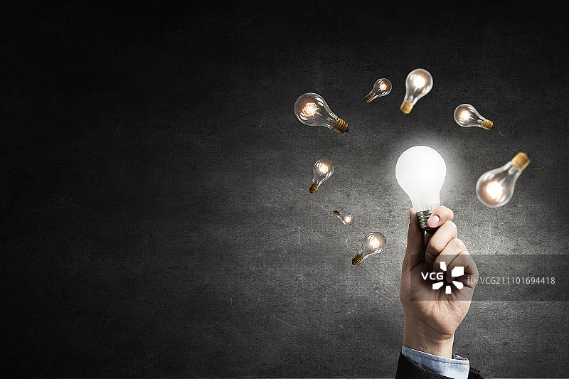 发光灯泡：手持黑暗中发光玻璃灯泡图片素材