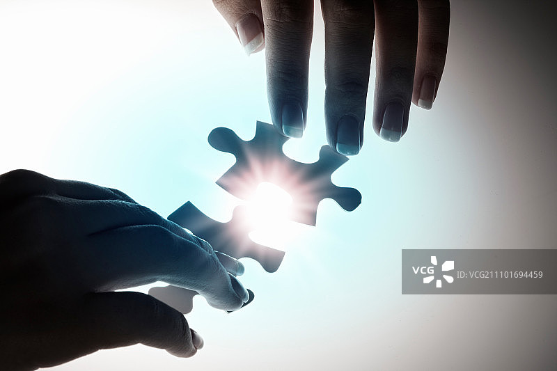 连接在一起：手部连接两块发光拼图图片素材