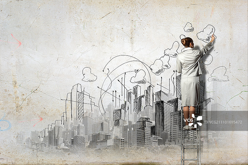 女商人在墙上绘画，站在梯子上绘制草图图片素材
