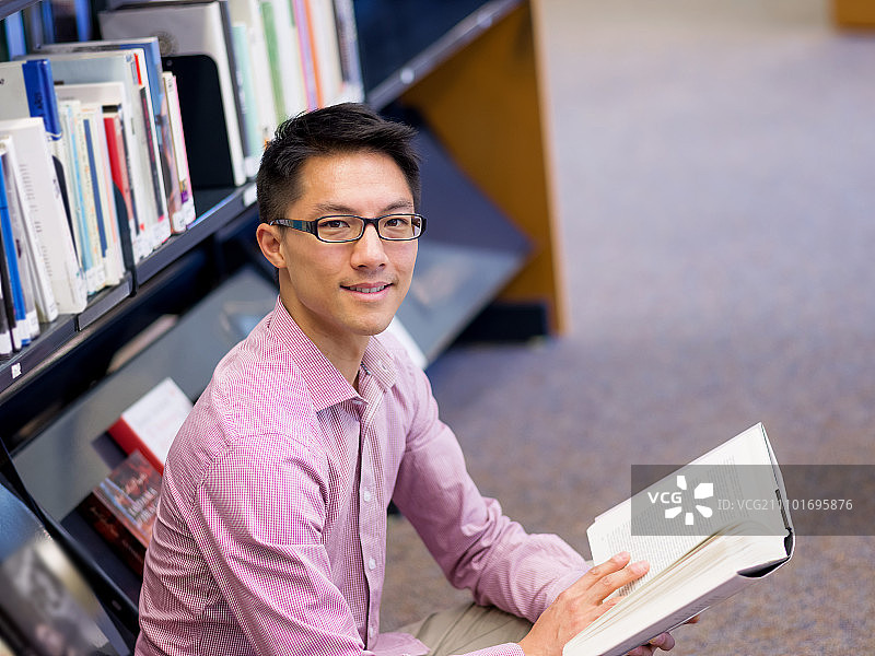 快乐的男学生在图书馆里拿着书图片素材