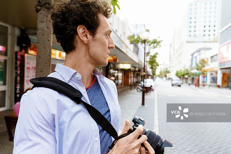 男摄影师正在拍照。专业摄影师在城市拍照图片素材
