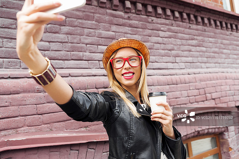 女孩在旅游景点参观，女子在城市街道用智能手机自拍图片素材