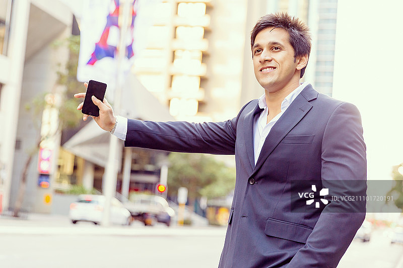 户外自信的商人肖像，手持手机图片素材