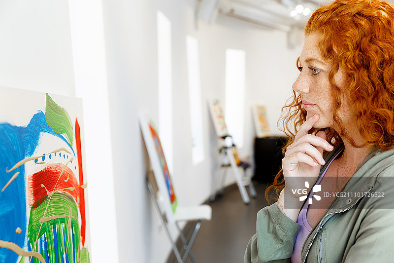 在画廊里站在绘画作品前的年轻白人女子图片素材