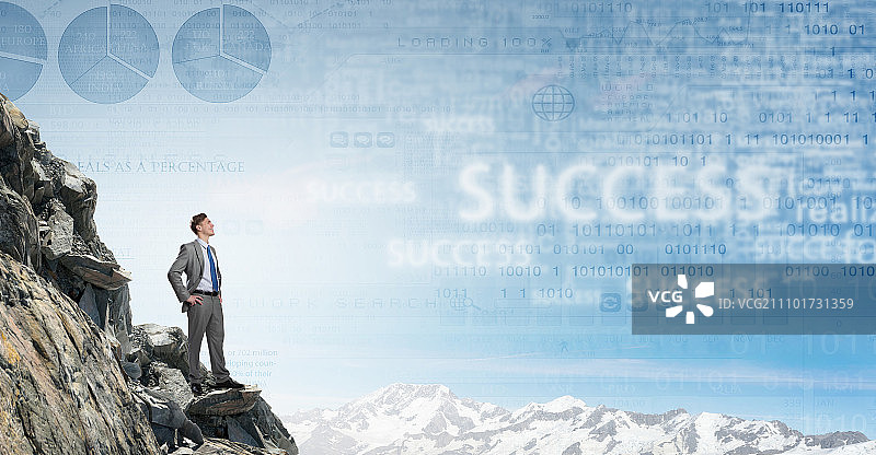 достиг вершины успеха. Молодой уверенный бизнесмен стоит на вершине скалы图片素材