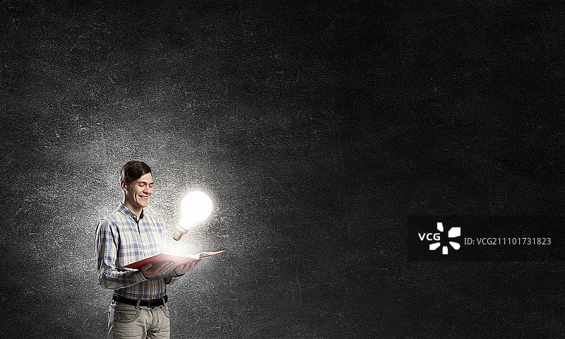 寻找灵感：年轻人手捧发光书籍图片素材