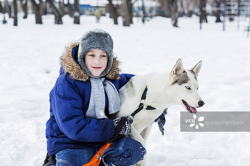 学龄儿童与小狗在冬季公园里，我最好的朋友和我图片素材