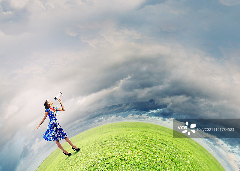 拿着扩音器的女人。穿着蓝色连衣裙的年轻女人在用扩音器讲话图片素材