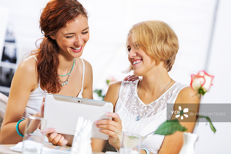 在咖啡馆使用平板电脑的两名年轻女子图片素材