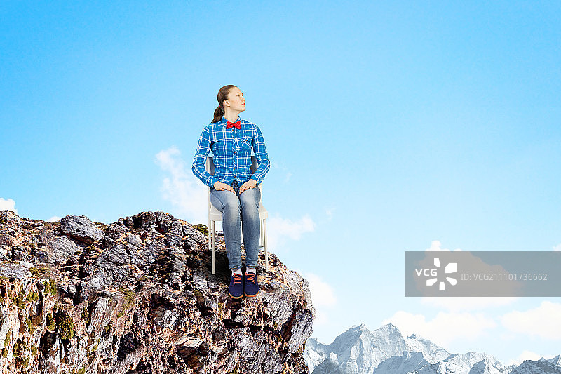 隔离概念：坐在岩石上的年轻女子图片素材
