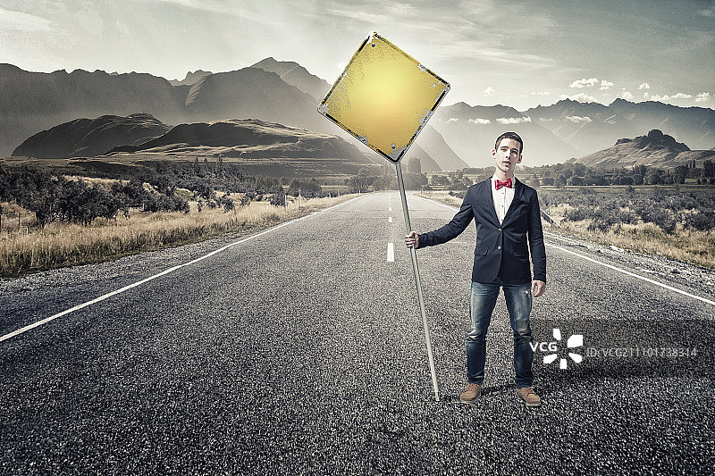 男人展示路标，穿着夹克和领结的年轻男人在路上举着牌子图片素材