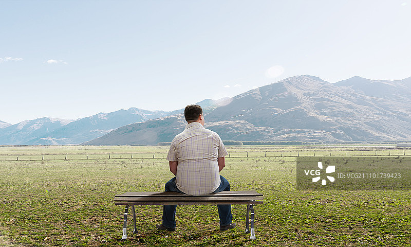 坐在长椅上背对远望的男人图片素材