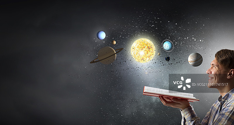 手捧书本的男人，年轻人手持打开的书本，周围环绕着旋转的太空星球图片素材