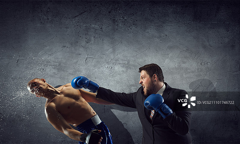 商业竞争精神：西装革履的商人在水泥房间里与对手搏斗图片素材